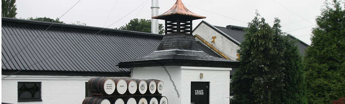 The Auchentoshan distillery with the barrels in front of the building with the kiln